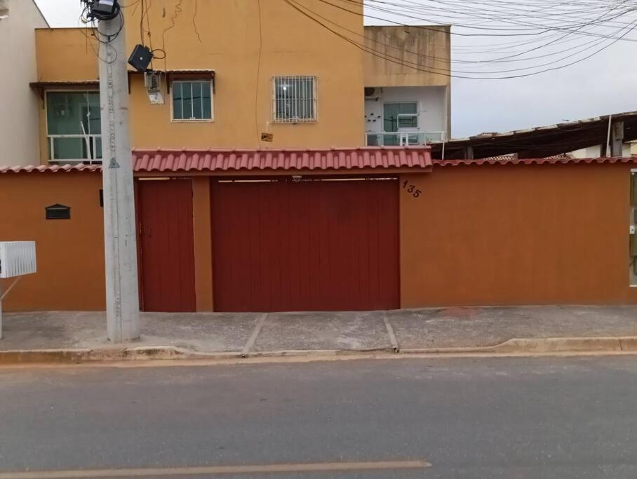 ein Gebäude mit einer roten Garagentür auf einer Straße in der Unterkunft Apartamento aconchegante in Rio das Ostras