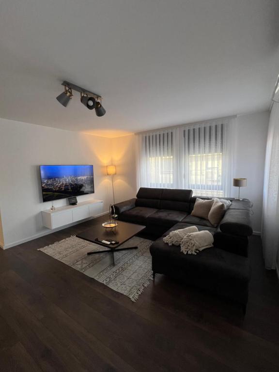 uma sala de estar com um sofá preto e uma televisão em Penthouse Centar em Novi Pazar