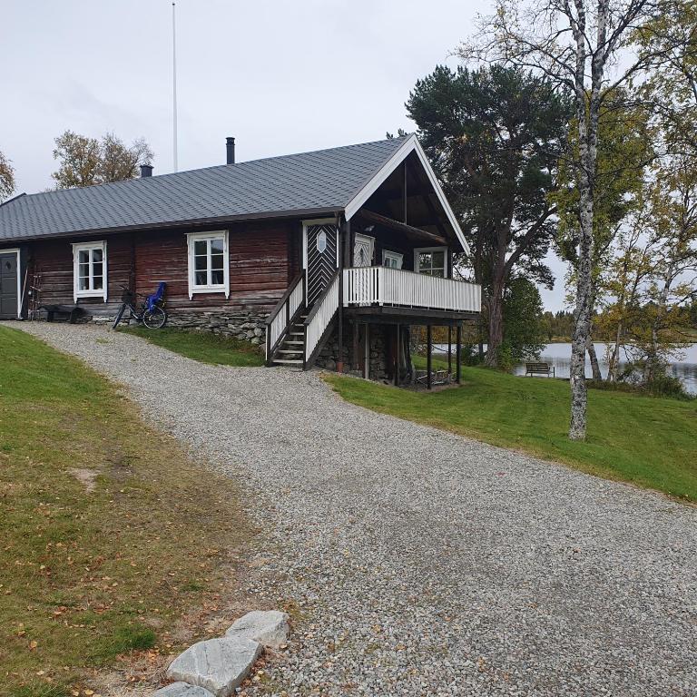 a log cabin with a porch on a gravel road at Brekkveien 81-meget sentral hytte,15 min å gå til Røros sentrum in Røros