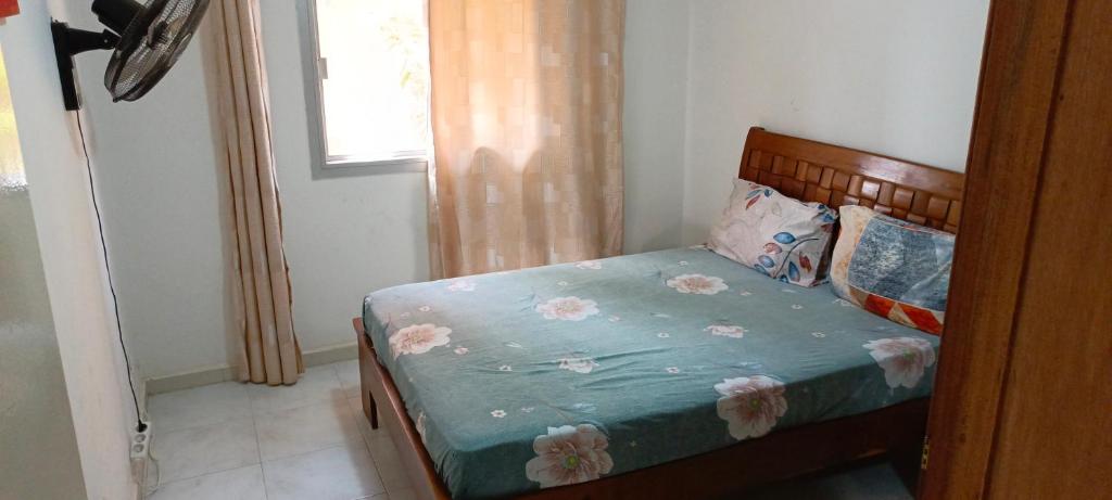 a bedroom with a bed with a blue comforter and a window at Jado house 4 in Dakar