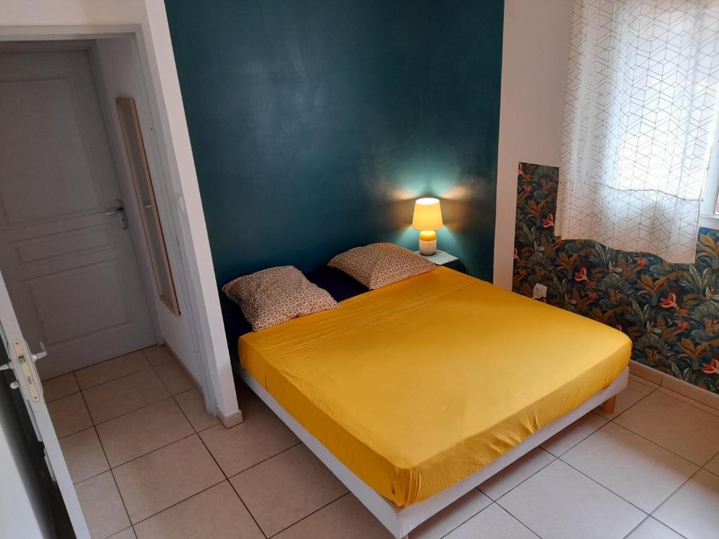 a bedroom with a yellow bed in a room at Appartement T3 proche aéroport et Nordev in Sainte-Clotilde