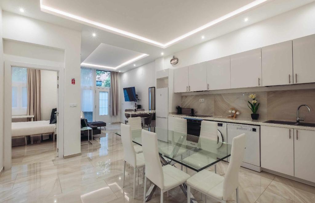 uma cozinha com uma mesa de vidro e armários brancos em Lujo exclusividad espacioso Madrid centro em Madri