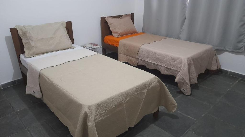 a room with two beds and an orange bed at Quarto com duas camas de solteiro in Itu