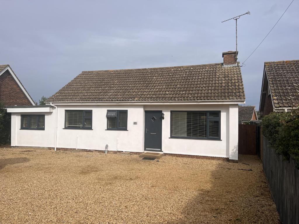 a white house with a black door in a yard at Inviting 2-Bed Bungalow in Heacham with spa bath in Heacham