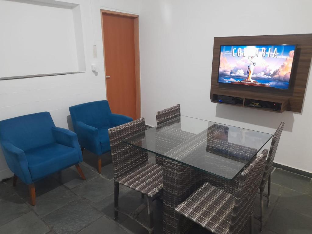 a dining room with a glass table and blue chairs at Quarto para 4 hóspedes in Itu