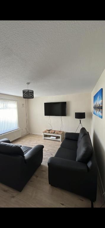 a living room with a couch and a flat screen tv at Entire 3 bedrooom holiday home in Liverpool
