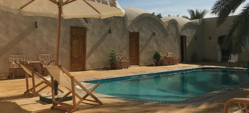 uma piscina com duas cadeiras e um guarda-sol em Best One - بيست ون em Siwa