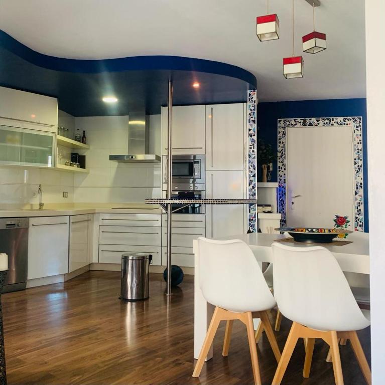 a kitchen with white cabinets and white chairs at Viernes Home in Torrox Costa
