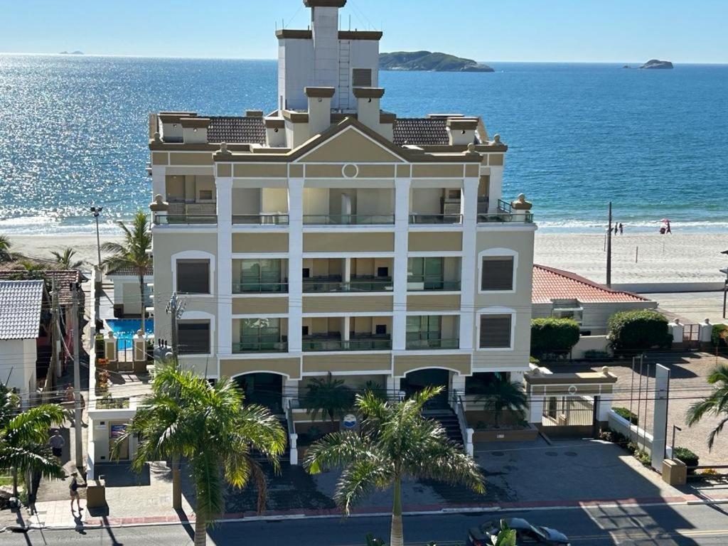a building on the beach with the ocean in the background at Golfinhos ApartHotel a beira-mar!! in Florianópolis