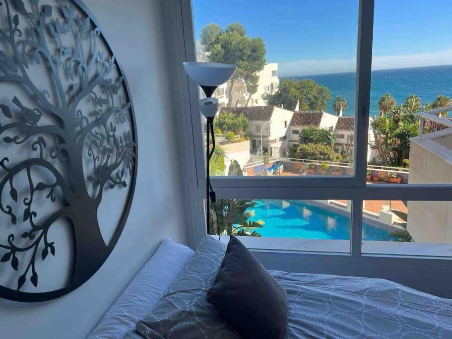 a bedroom with a window with a view of a pool at Frente al Mar y Paseo marítimo en el centro Marbella in Marbella