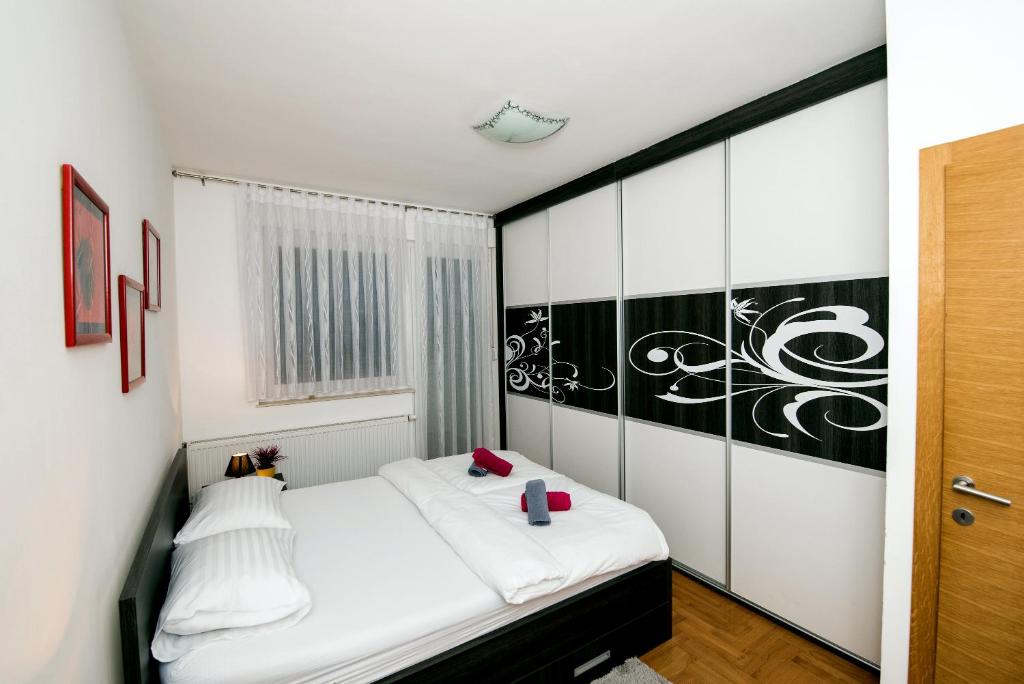 ein Schlafzimmer mit einem weißen Bett und einer schwarz-weißen Wand in der Unterkunft City Osijek, CENTAR, SELF CHECK IN in Osijek