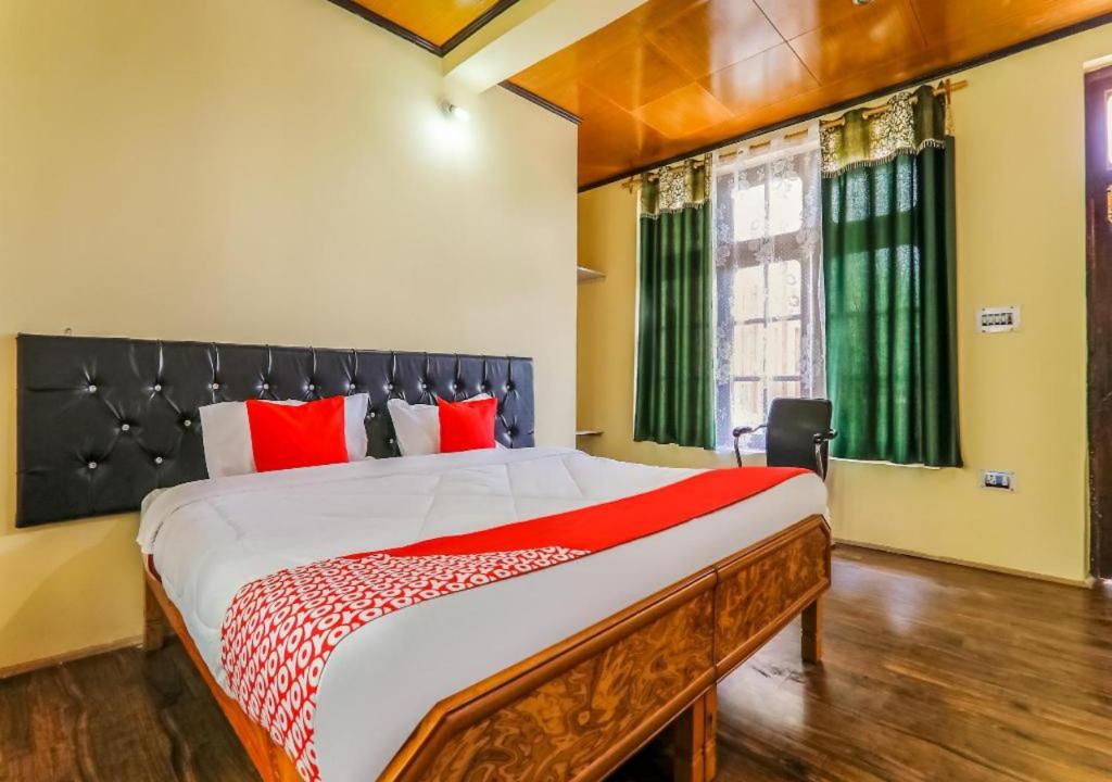 a bedroom with a large bed with red pillows at Guest House Naazh in Leh