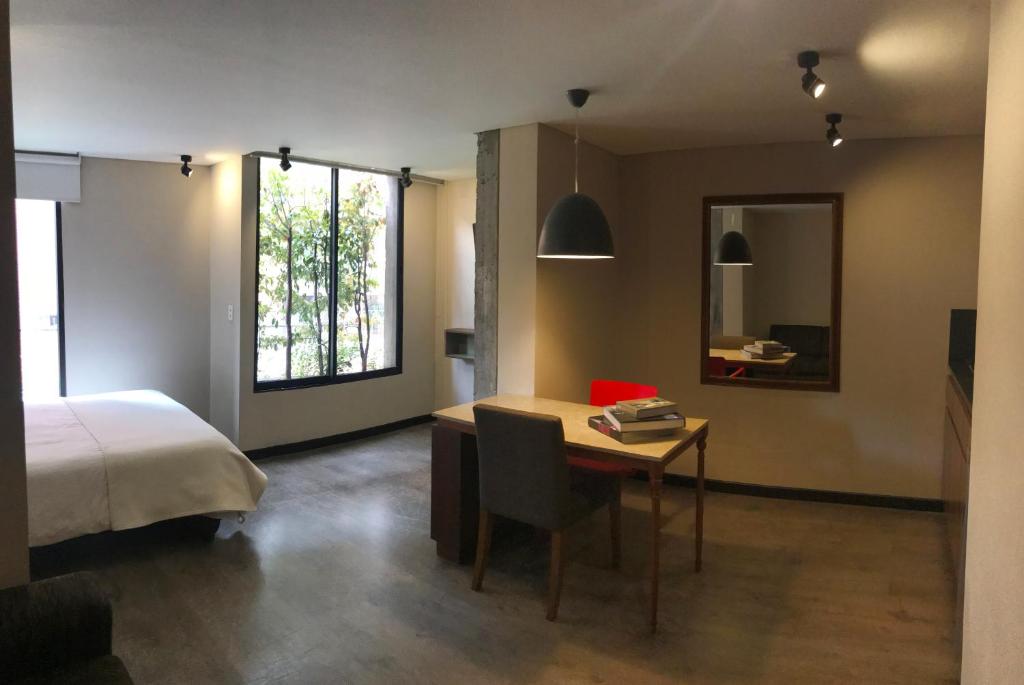 een slaapkamer met een bed, een bureau, een bed en een raam bij Apartach Apartment 302 in Bogota