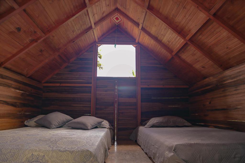 2 łóżka w drewnianym pokoju z oknem w obiekcie Jardin del sol Ecoglamping w mieście San José de Suaita