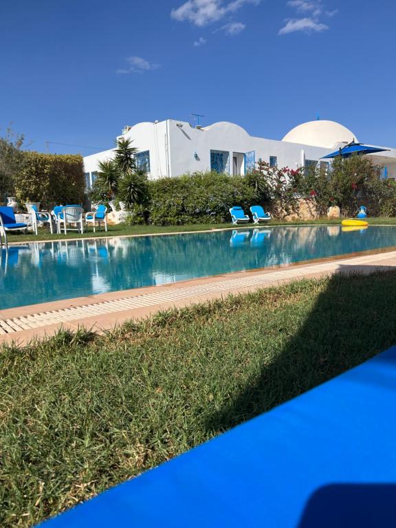 a swimming pool with chairs and a house in the background at Maison eirene in Hammamet