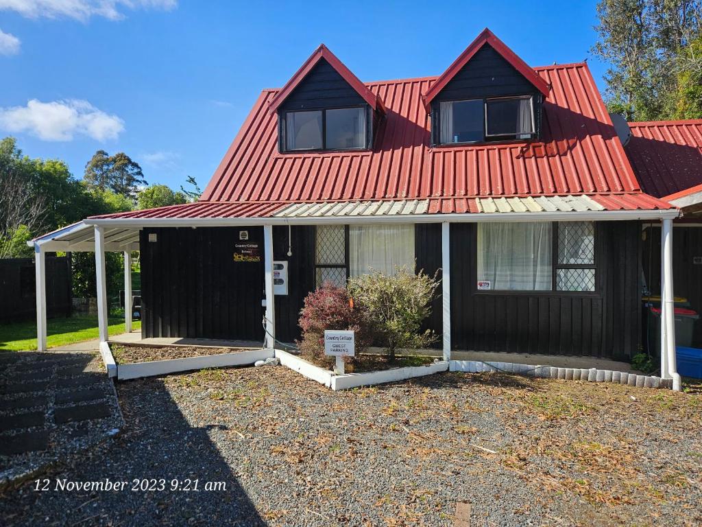 una casa con techo rojo en Country Cottage Rotorua, en Whakatahuri