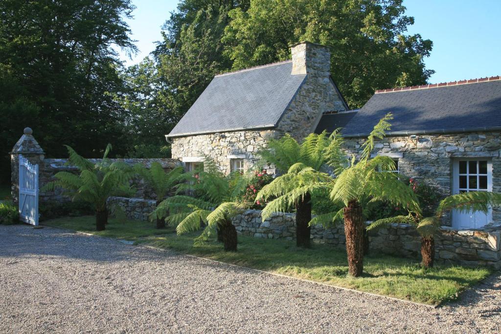 a stone house with palm trees in front of it at Gîte des Fougères in Cherbourg en Cotentin