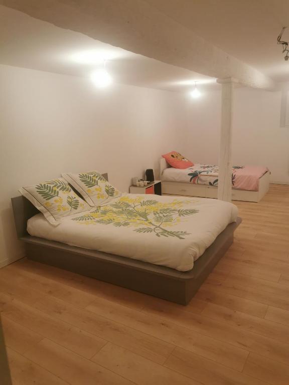 2 camas en una habitación con suelo de madera en Maison de village, en Ventenac-Cabardès