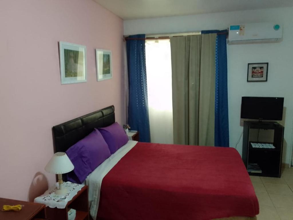 a bedroom with a bed with purple sheets and a television at APART OBELISCO CENTRO AA Wi Fi in Buenos Aires