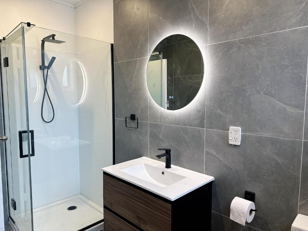 ein Bad mit einem Waschbecken, einer Dusche und einem Spiegel in der Unterkunft 4 Bedrooms Escape, close to CBD in Rotorua