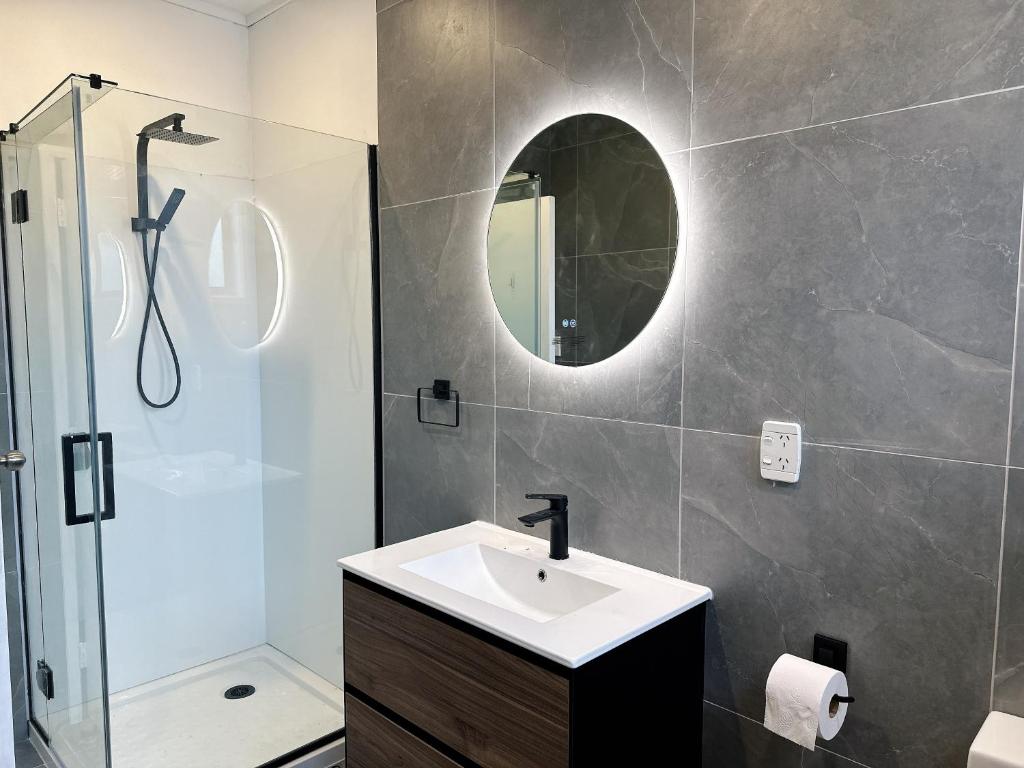 a bathroom with a sink and a shower and a mirror at 4 Bedrooms Escape, close to CBD in Rotorua