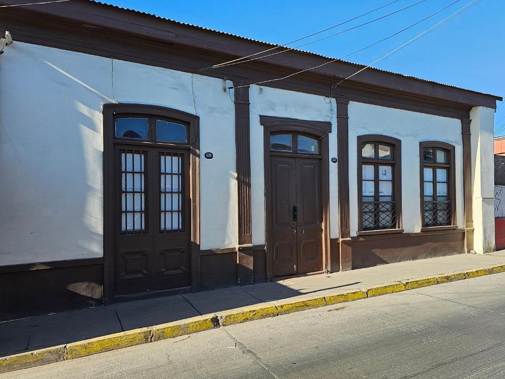 a white building with brown doors on a street at Casa en casco Historico Portal Del Valle in La Serena