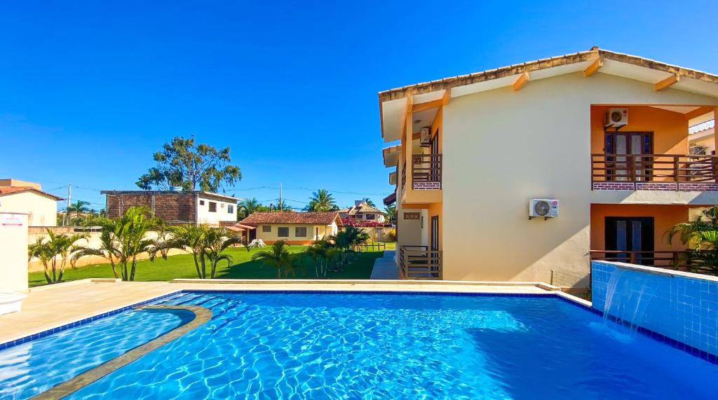 a villa with a swimming pool in front of a house at Residencial Malibu in Porto Seguro