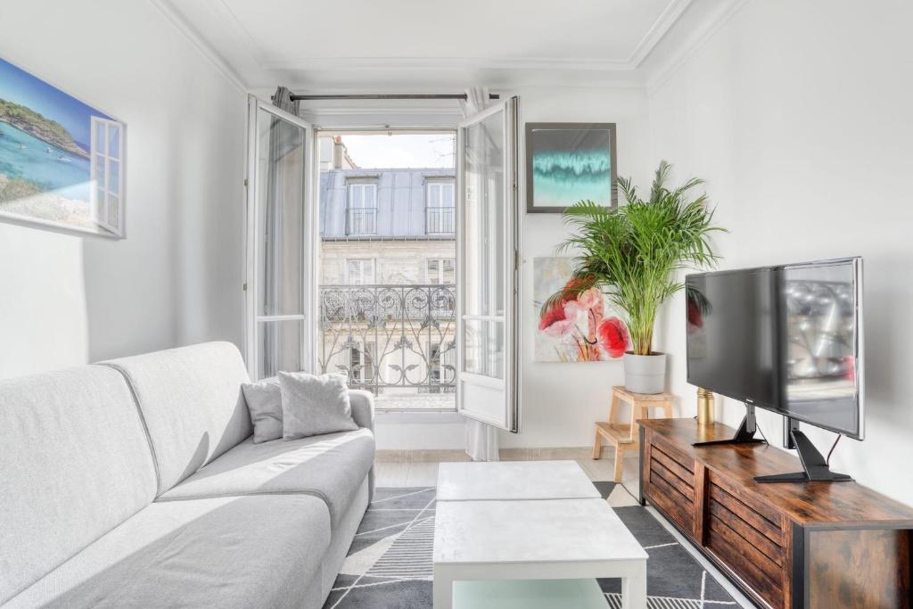 un salon avec un canapé et une télévision dans l'établissement Grand Appart Spacieux Rénové Paris Métro Wifi, à Paris