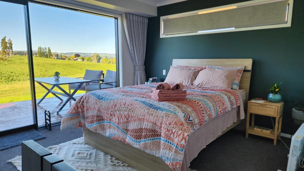 a bedroom with a bed and a table and a large window at A stunning retreat in Rotorua! in Rotorua