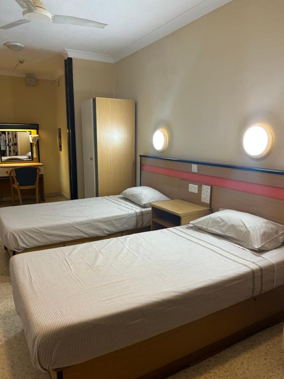 two beds in a hotel room with lights on the wall at EA holiday beds in St Julian's