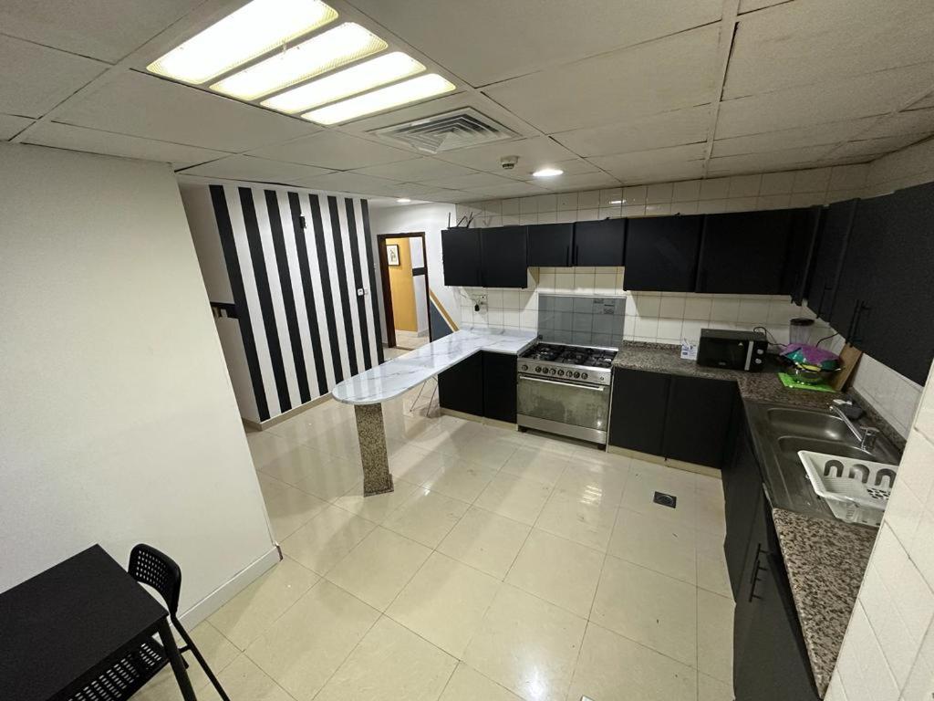 a kitchen with black and white cabinets and a stove at Short Stay Partition Room in Al Barsha 1 Near Mashreq Metro in Dubai