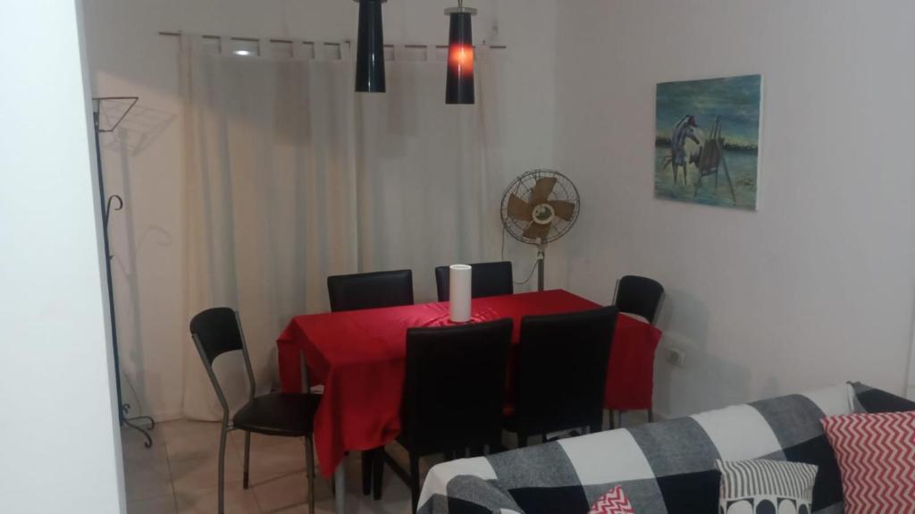 una sala da pranzo con tavolo rosso e sedie nere di Torres sarmiento un dormitorio a Resistencia