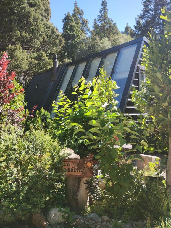 une maison avec beaucoup de plantes dans la cour dans l'établissement La Dorita cabaña de montaña, à San Carlos de Bariloche