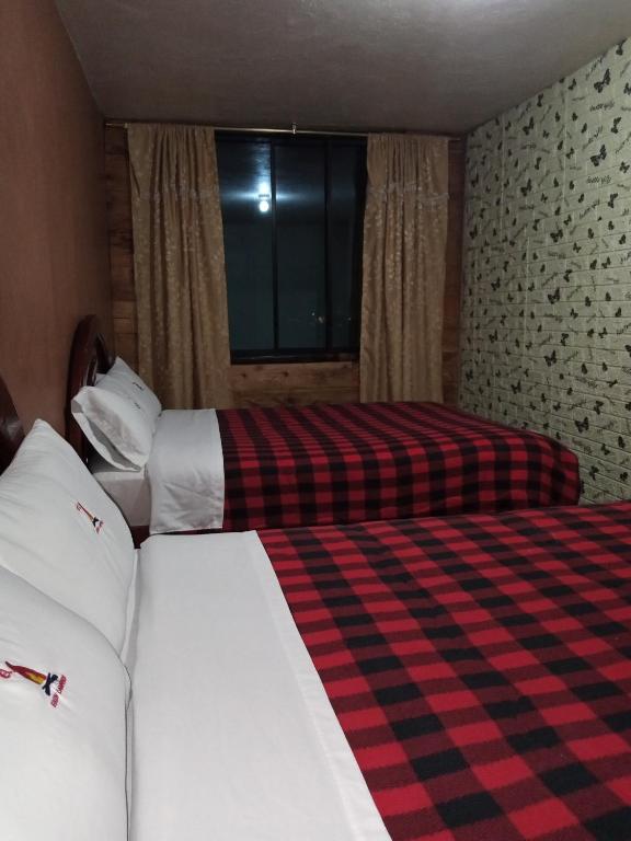 Habitación de hotel con 2 camas y ventana en Hostal Restaurante el Fogón Campero en Papallacta