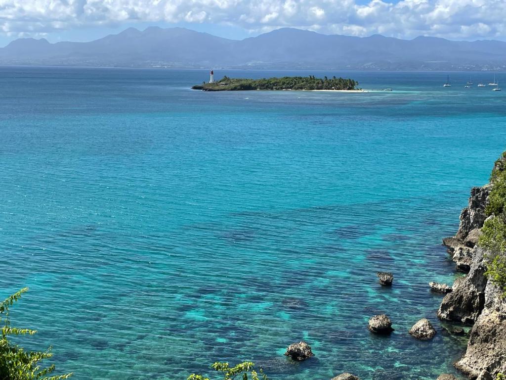 a large body of water with a lighthouse on an island at Face à la mer in Le Gosier