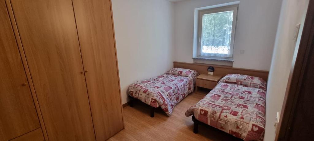 a small bedroom with two beds and a window at La Betulla Apartments in Commezzadura