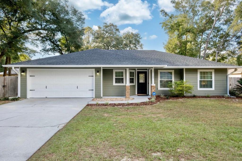 a green house with a white garage at Newly Reno'd High Springs Haven in High Springs