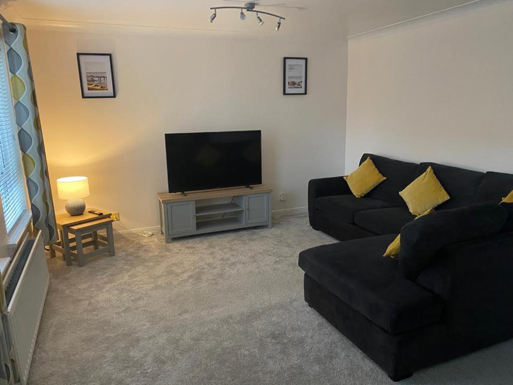 a living room with a black couch and a flat screen tv at Great Location, large 1 bed flat with parking in Broughty Ferry