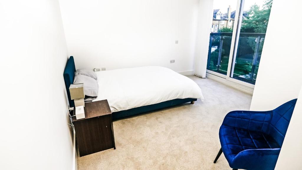 ein Schlafzimmer mit einem Bett und einem blauen Stuhl in der Unterkunft Modern Spacious 2-Bed Apartment in London in Bromley