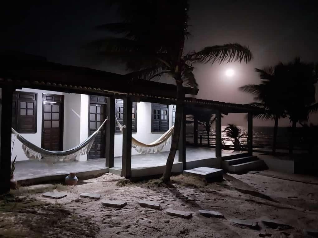 a house with hammocks and a palm tree at night at Pousada Marinheiro in Sítio