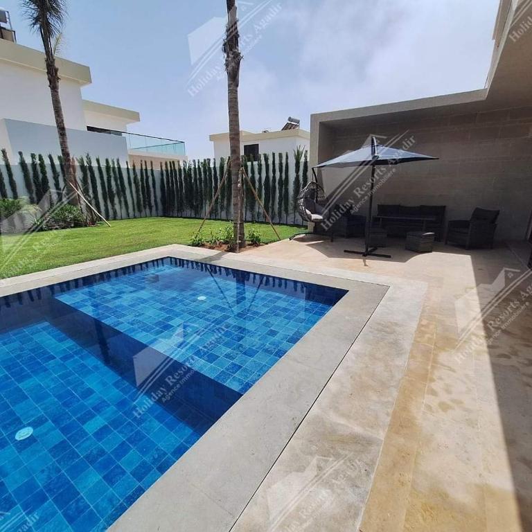 a swimming pool in a villa with an umbrella at Blue Haven Villa 4 bedroomTaghazout Bay Amda in Taghazout