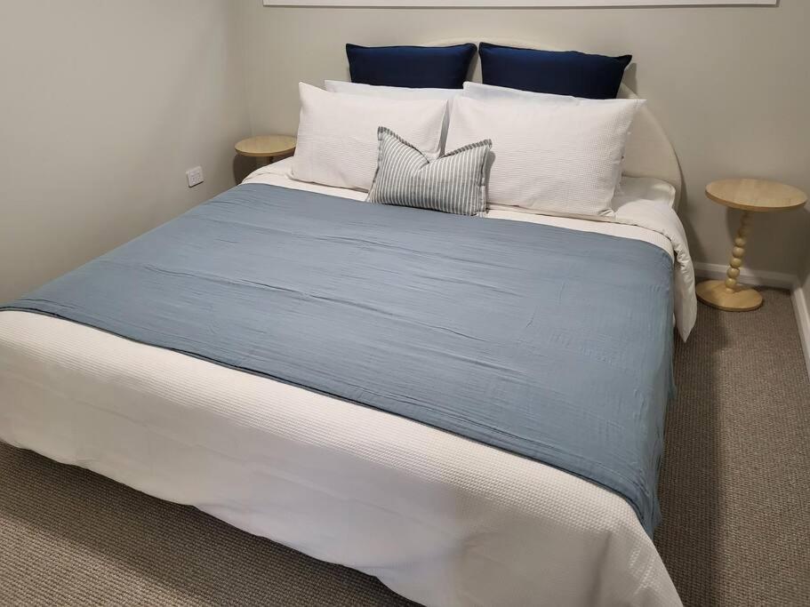 a large bed with blue and white sheets and pillows at Coastal Pod in Port Macquarie
