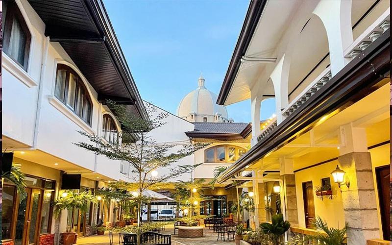 a group of buildings with tables and chairs in a courtyard at Solano Hotel & Resort At Casa Ysabel in Lipa