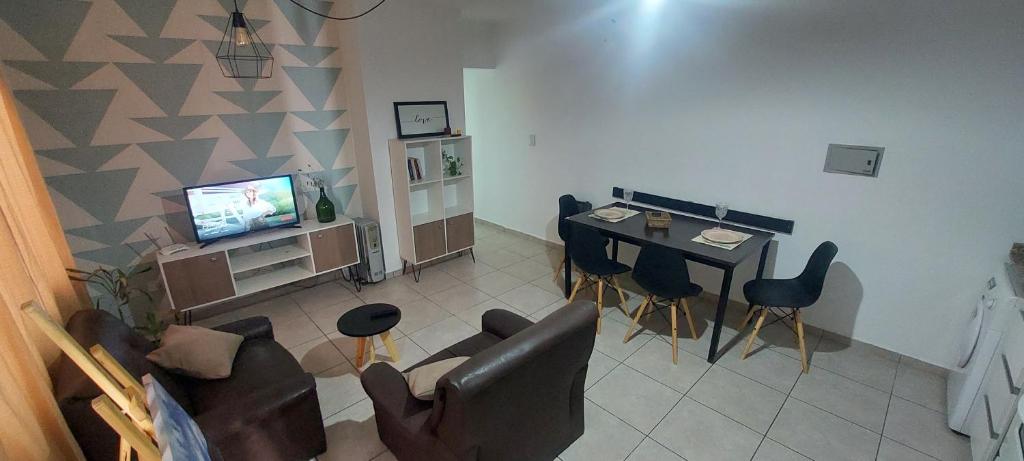 ein Wohnzimmer mit einem Tisch, Stühlen und einem TV in der Unterkunft Depto armani in Godoy Cruz