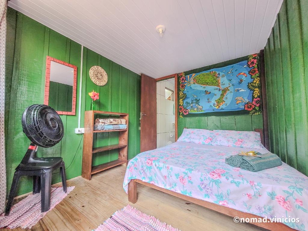 um quarto com paredes verdes, uma cama e uma ventoinha em Quarto do Madruga na Ilha do Mel
