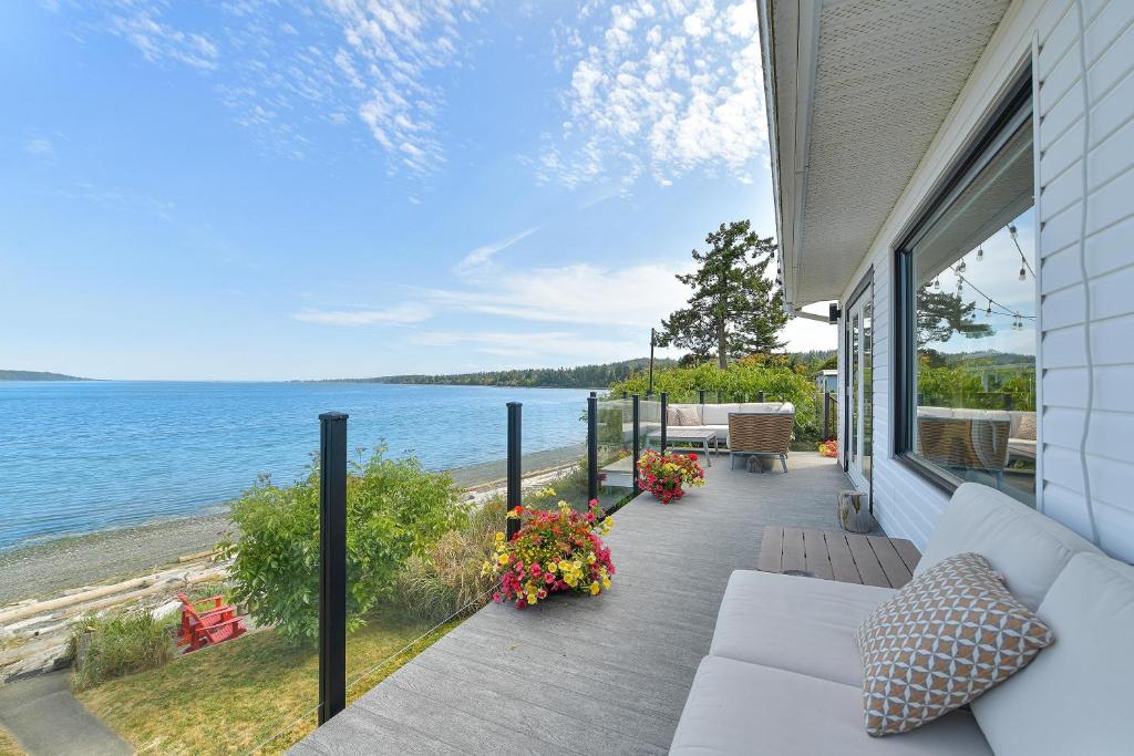 a porch with a couch and a view of the ocean at Bazan Bay Beach House in North Saanich
