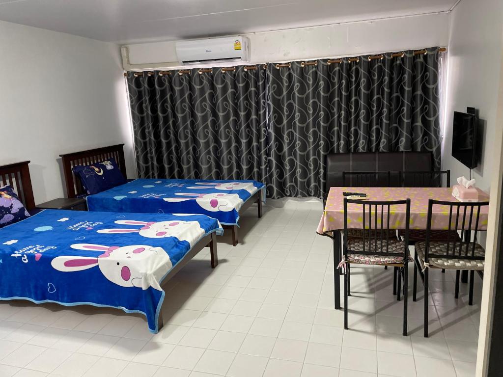 a room with two beds and a table and a table and chairs at Muangthong C6,C7,C8 near IMPACT in Nonthaburi