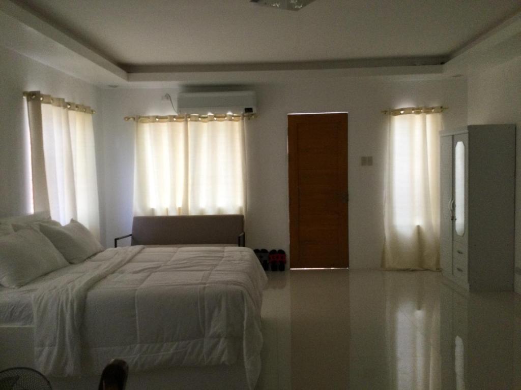 a bedroom with a bed with white sheets and windows at Gengs Apartment and Nmax Rentals in Dipolog