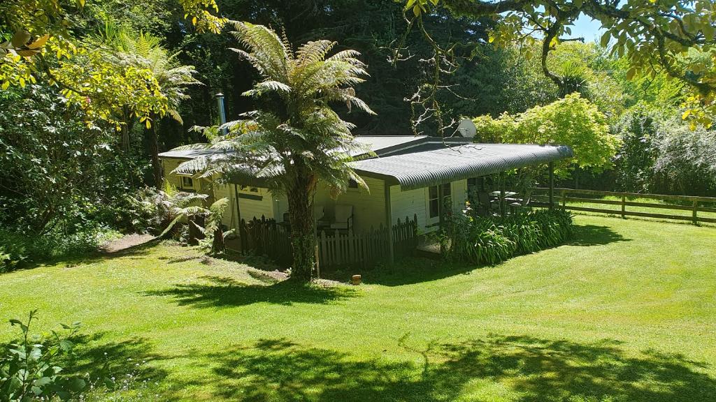 une petite maison avec un palmier dans une cour dans l'établissement Poihipi Farm Stay, 