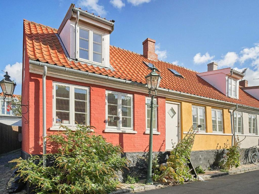 uma casa vermelha e amarela com um telhado laranja em Holiday home Rønne VI em Rønne